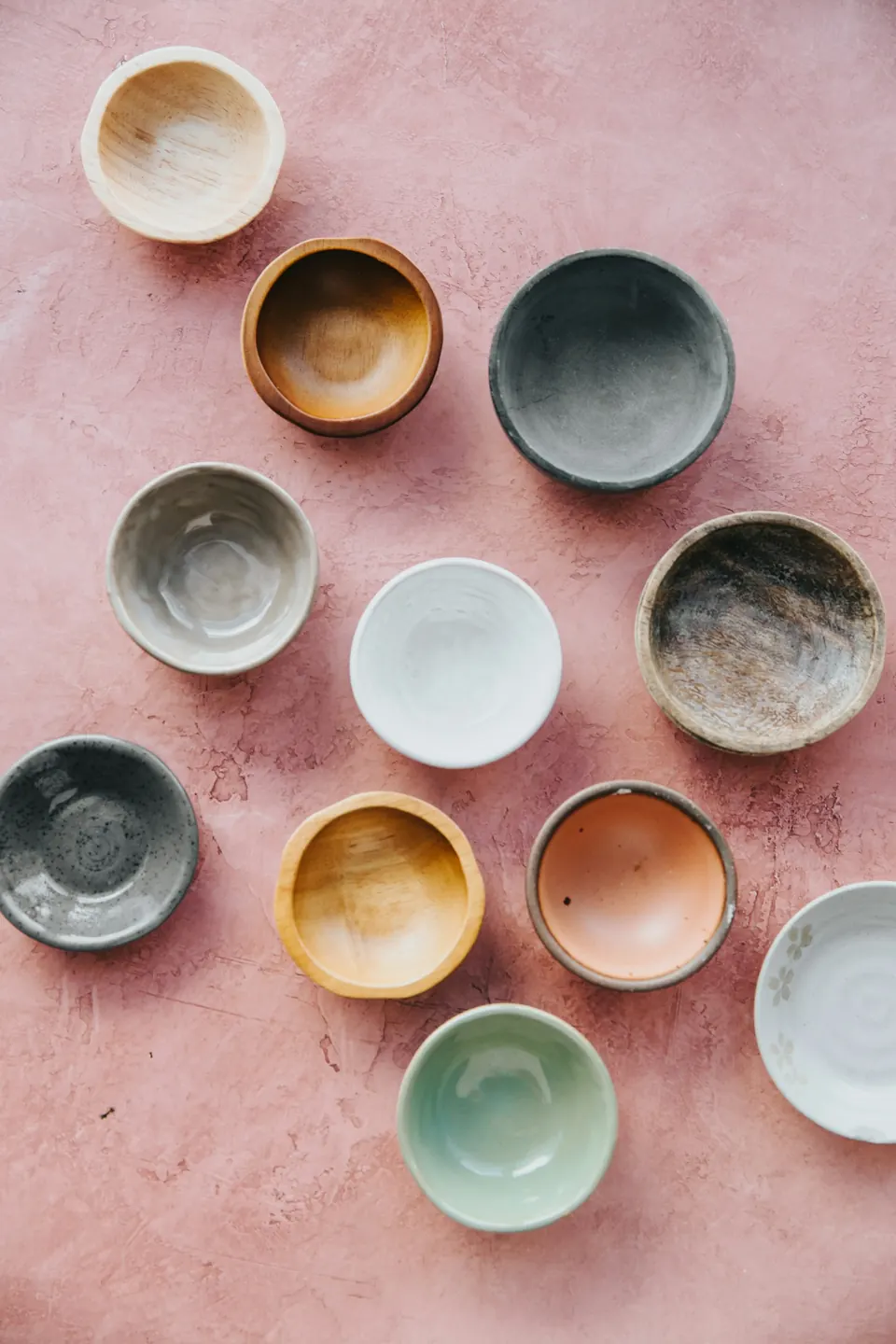 Small bowls in many glazes on a pink surface